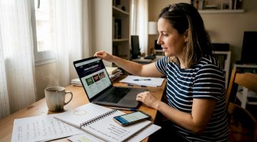 Una mujer revisa diferentes páginas de casinos online desde su escritorio en casa, buscando información y comparando opciones.